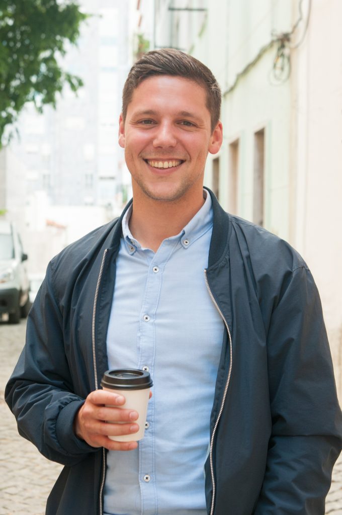 homme avec une chemise bleu tenant un café dans sa main 